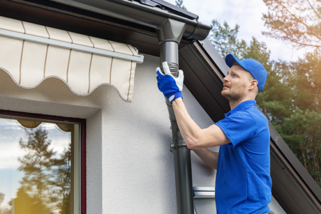 Worker installing house roof rain gutter system